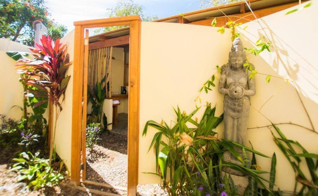 Galería Suites San Pancho: garden entrance to a suite, with a wooden door and a stone sculpture