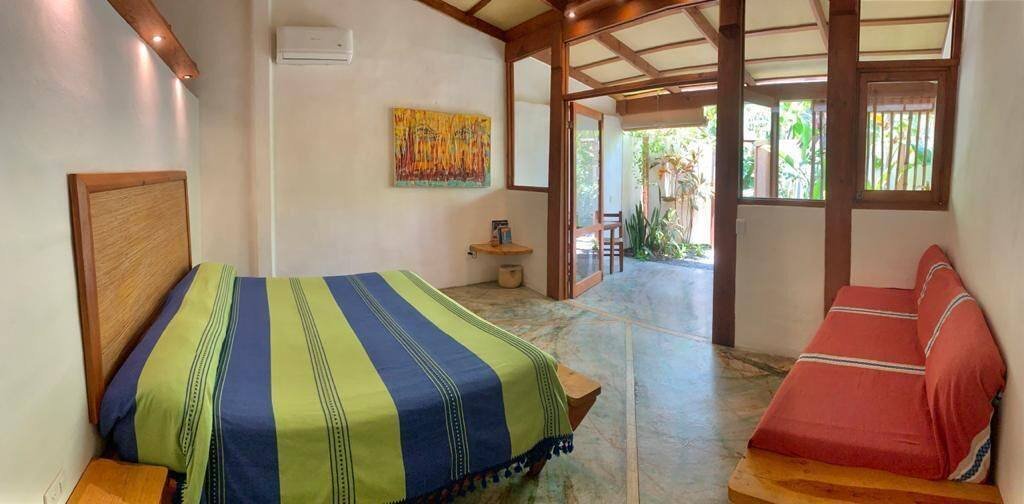 Galería Suites San Pancho: suite with a striped bedspread and a small sofa
